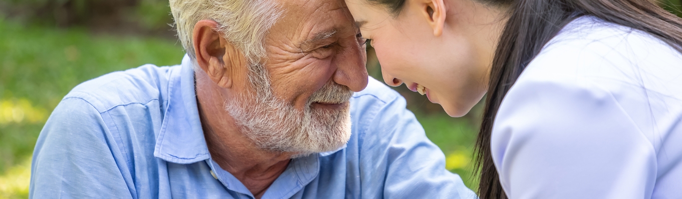 older gentleman and younger woman looking touching foreheads while looking endearingly at eachother