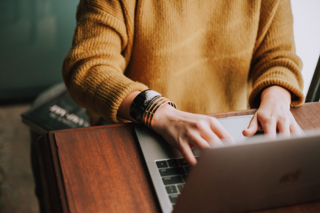 Person sitting at a desk typing on a laptop.