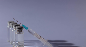 An image of a syringe resting on four medication vials