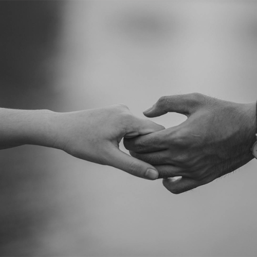 Two hands, one gently pulling the other