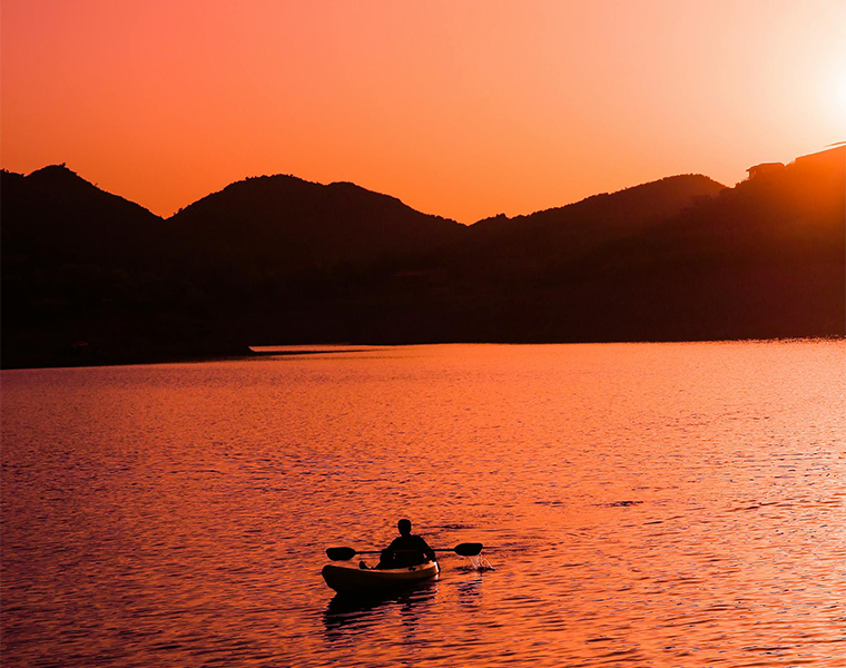 An image of a kayaker on a lake a sunset